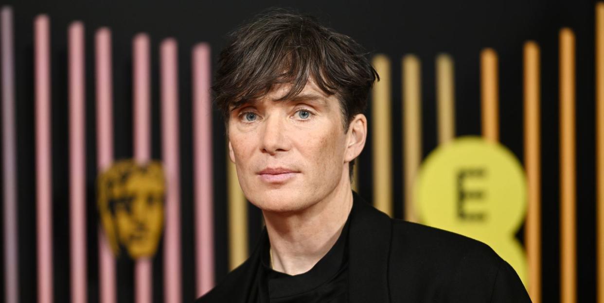 cillian murphy stands in front of a bafta and ee branded background at the bafta film awards