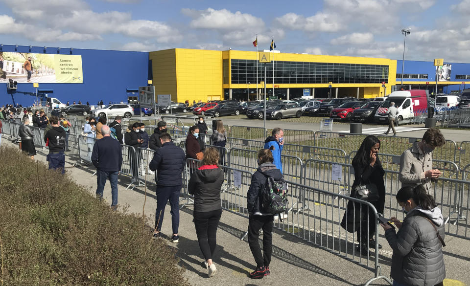 People stand in line for last minute shopping outside an Ikea store in Brussels, Friday, March 26, 2021. New rules for non-essential shopping begin on Saturday in Belgium as the nation tries to reduce its fast-rising COVID-19 numbers. Beginning Saturday customers will need to book an appointment to be allowed inside all non-essential businesses. (AP Photo/Mark Carlson)