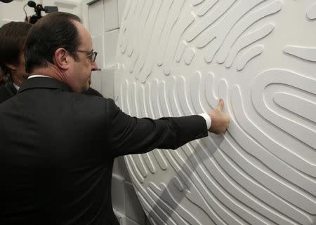 French President Francois Hollande puts his thumbprint on a wall at the Nicolas Hulot Foundation stand in the Climate Generations area during the World Climate Change Conference 2015 (COP21) at Le Bourget, near Paris, France, December 1, 2015. REUTERS/Philippe Wojazer