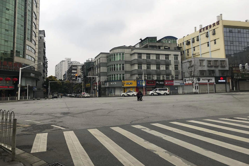 In this photo provided to the Associated Press, a person on a scooter crosses an empty intersection in Wuhan in central China's Hubei Province, Monday, Jan. 27, 2020. China on Monday expanded sweeping efforts to contain a viral disease by extending the Lunar New Year holiday to keep the public at home and avoid spreading infection. (AP Photo)