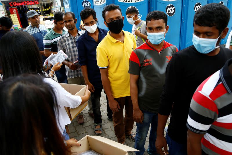 Migrant workers from Bangladesh queue to collect free masks and get their temperatures taken in Singapore