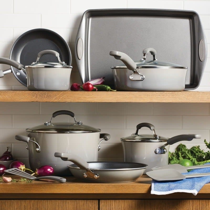 Various cookware pieces including pots, pans, and lids on wooden shelves in a kitchen setting