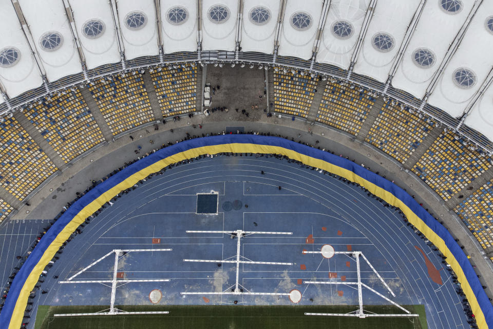 A 200 meters long Ukrainian flag is unfolded at the Olympiyskiy stadium in Kyiv, Ukraine, Wednesday, Feb. 16, 2022. As Western officials warned a Russian invasion could happen as early as today, the Ukrainian President Zelenskyy called for a Day of Unity, with Ukrainians encouraged to raise Ukrainian flags across the country. (AP Photo/Evgeniy Maloletka)