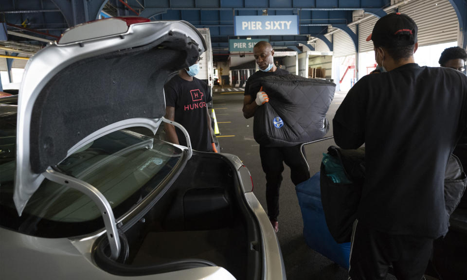 A worker loads an insulated container of prepackaged meals into a car for delivery to needy families in New York, Tuesday, July 7, 2020. Catering startup HUNGRY is feeding the stuck-at-home elderly and low-income kids, reaching 10,000 homes a day. (AP Photo/Mark Lennihan)