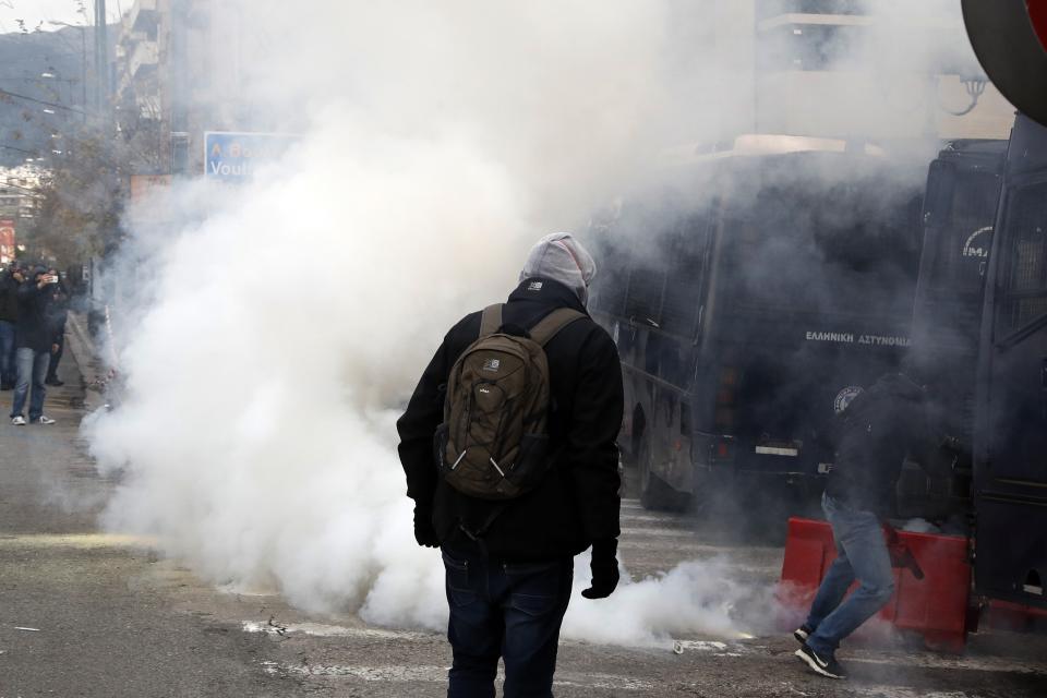 Riot police throw a tear gas canister at teachers and other protesters, during clashes near the Prime Minister's office in Athens, Friday, Jan. 11, 2019. About 1,500 people took part in the protest. Teachers' unions oppose the government's selection process for the planned hiring of 15,000 new teachers over the next three years. (AP Photo/Thanassis Stavrakis)