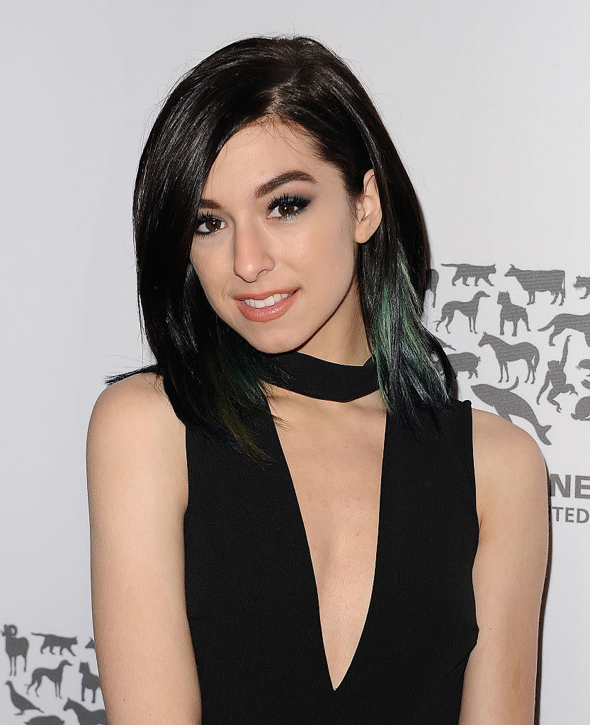 Woman in sleeveless black outfit with a keyhole neckline, smiles with shoulder-length hair