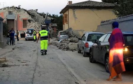 People stand along a road following a quake in Amatrice, central Italy, August 24, 2016. REUTERS/Emiliano Grillotti