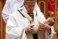 Pope Francis holds a statue of baby Jesus during the Christmas night Mass in Saint Peter's Basilica at the Vatican December 24, 2016. REUTERS/Tony Gentile