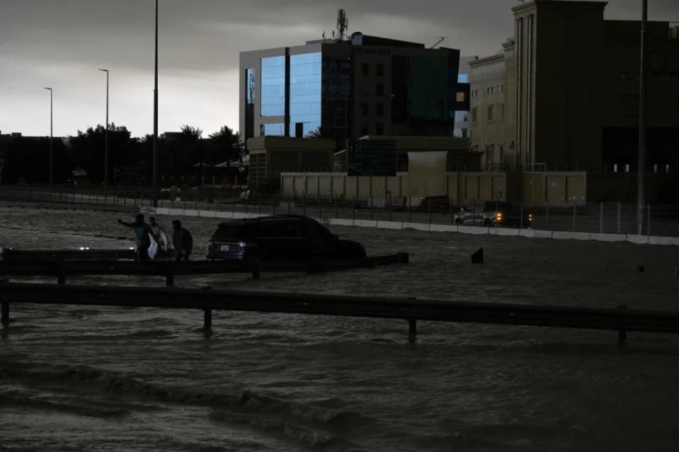 Hombres intentan remolcar un vehículo para sacarlo del agua estancada en Dubai, Emiratos Árabes Unidos, el martes. (Jon Gambrell/AP)