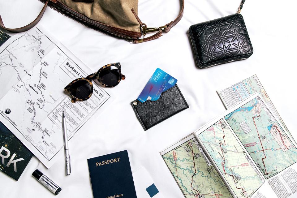 An American Express Hilton Honors card with travel documents and necessities
