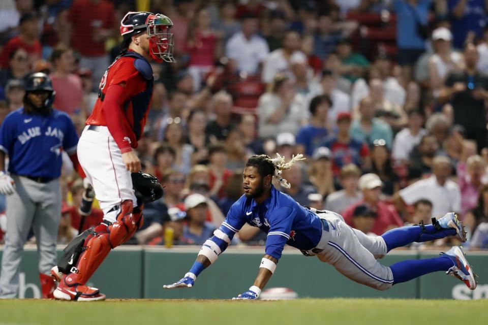 Toronto Blue Jays' Raimel Tapia slides into home plate on his inside-the-park grand slam, next to Boston Red Sox's Kevin Plawecki during the third inning of a baseball game, Friday, July 22, 2022, in Boston. (AP Photo/Michael Dwyer)