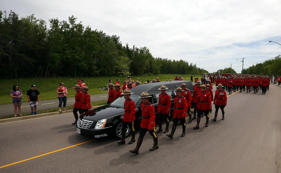 Royal Canadian Mounted Police officers march beside a hearse during a funeral procession for three fellow officers who were killed last week in Moncton