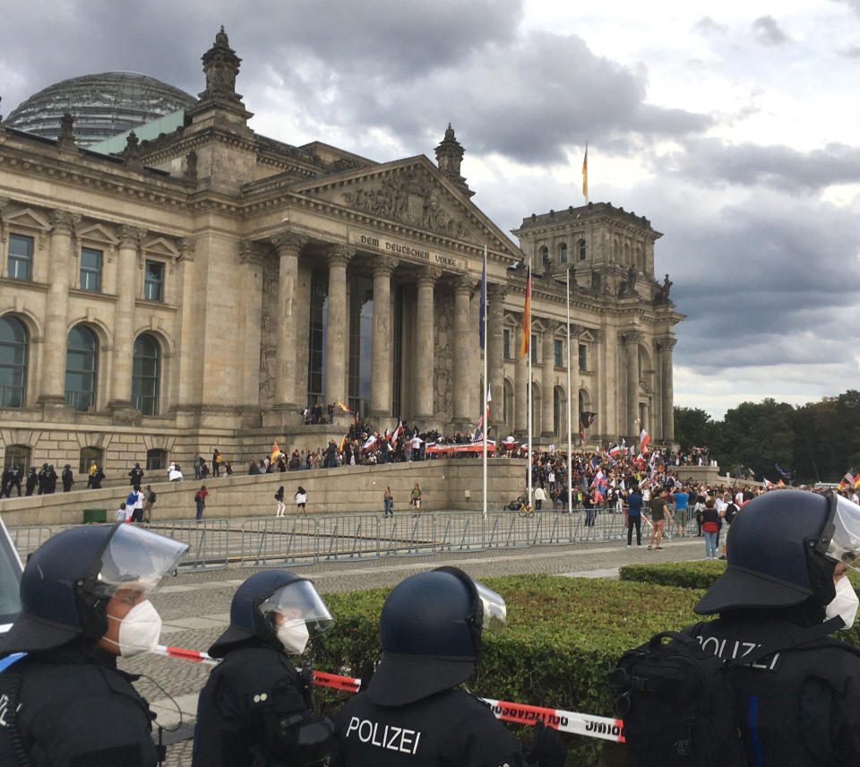 Police officers looks to protestors standing on the steps in front of the Reichstag building during a demonstration against the Corona measures in Berlin, Germany, Saturday, Aug. 29, 2020. (Lukas Dubro/dpa via AP)