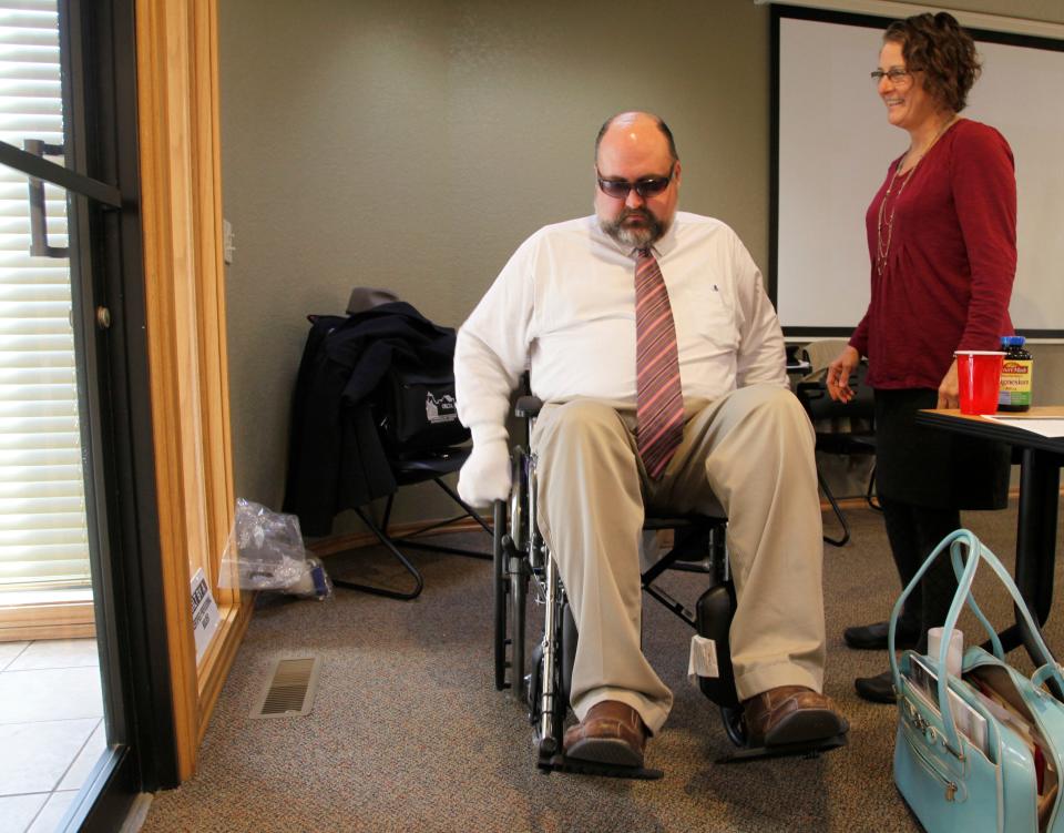 Richard Mize, senior business writer for The Oklahoman, seven years (and 100 pounds) ago, wears dark glasses smeared with hand lotion to simulate loss of vision, and socks with tennis balls on his hands to simulate advanced arthritis, while maneuvering a wheelchair through a doorway during a class for the National Association of Home Builders’ Certified Aging-in-Place Specialist designation at the Oklahoma Home Builders Association. Guiding him is Kendra Orcutt, occupational therapist and aging-in-place specialist.