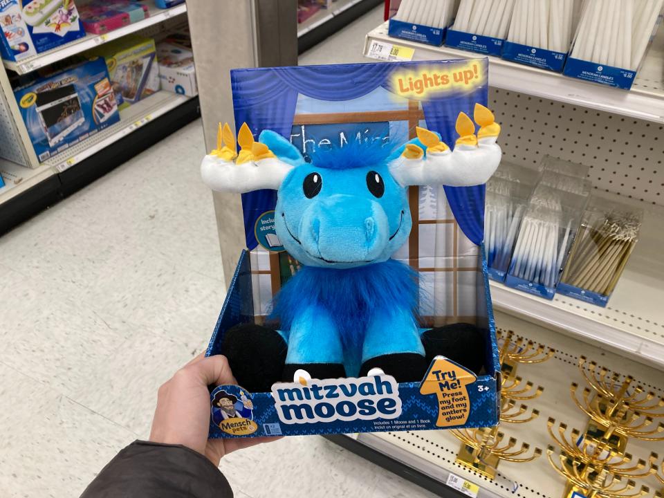 A blue moose stuffed animal with fake candles on its antlers.