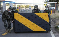 South Korean marines place a barricade for traffic control after a sailor of the unit was confirmed to have been infected with the coronavirus in front of a Navy unit on Jeju Island, South Korea, Friday, Feb. 21, 2020. South Korea on Friday declared a "special management zone" around a southeastern city where a surging viral outbreak, largely linked to a church in Daegu, threatens to overwhelm the region's health system. (Park Ji-ho/Yonhap via AP)