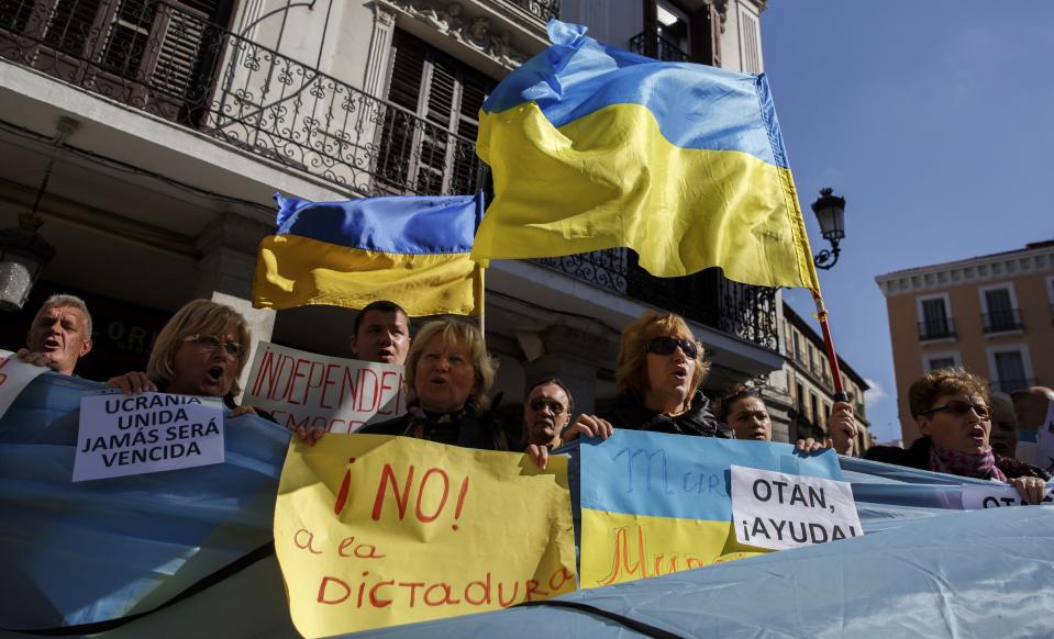 Protestors wave Ukraine flags and shout slogans against Russia in front of the foreign ministry in Madrid