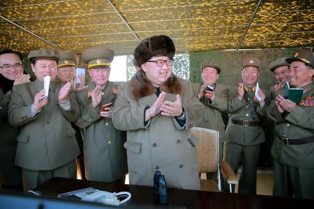 North Korean leader Kim Jong Un claps during a demonstration of a new large-caliber multiple rocket launching system at an unknown location, in this undated photo released by North Korea's Korean Central News Agency (KCNA) on March 22, 2016. REUTERS/KCNA/File Photo