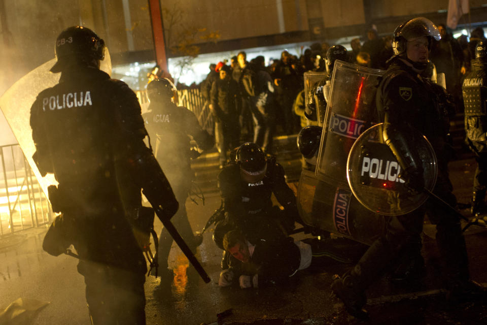 Riot police detain protesters outside the parliament building in Ljubljana, Slovenia, Friday, Nov. 30, 2012. Thousands joined anti-government protests in Slovenia on Friday as tensions soared ahead of this weekend's presidential runoff in the small, economically struggling EU nation. (AP Photo/Matej Leskovsek)