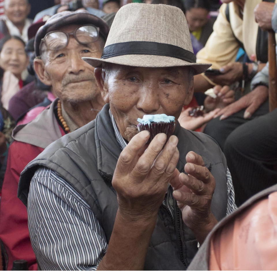 A Tibetan man in exile enjoys a sweet treat during the Dalai Lama birthday celebrations in Mcledoganj, India on July 6, 2016 (Rex)