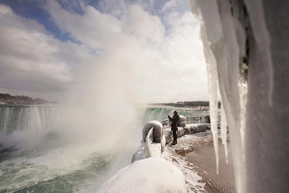 A woman takes a photo at the Horseshoe Falls in Niagara Falls, Ontario, on January 27, 2021. (Photo by Geoff Robins / AFP) (Photo by GEOFF ROBINS/AFP via Getty Images)