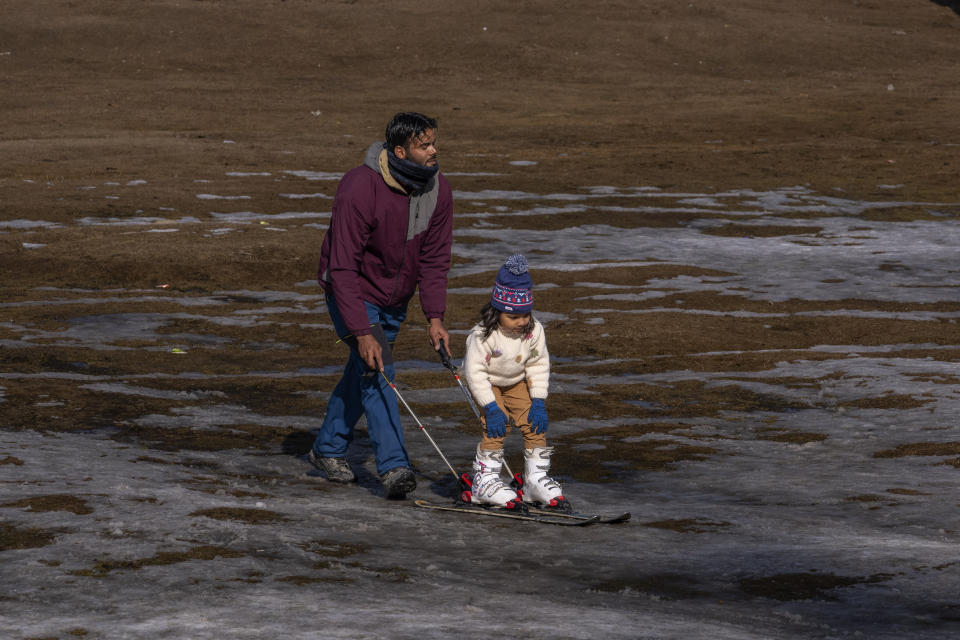 FILE - A Kashmiri ski instructor helps a young tourist to ski on a patch of snow in Gulmarg, northwest of Srinagar, Indian controlled Kashmir, Jan. 13, 2024. While the U.S. is shivering through bone-chilling cold, most of the rest of world is feeling unusually warm weather. Scientists Tuesday, Jan. 16, say that fits with what climate change is doing to Earth. (AP Photo/Dar Yasin, File)