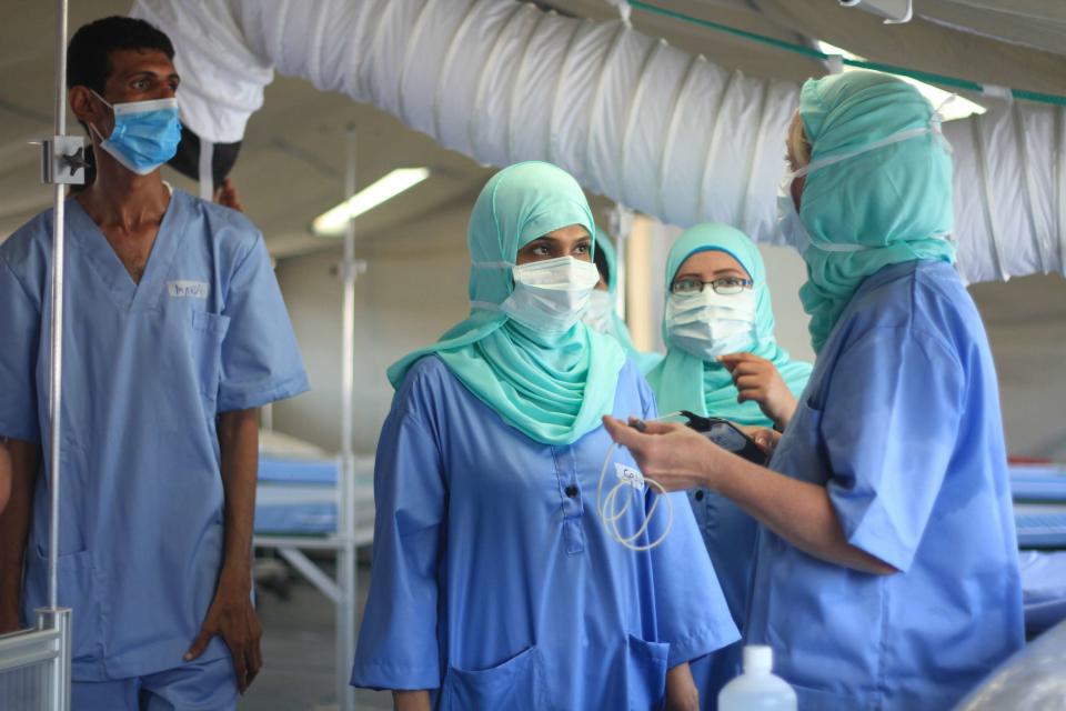 In this photo provided by the International Committee for the Red Cross International and Yemeni staff stand inside a new field hospital for coronavirus patients in the country's main southern city of Aden. The Red Cross announced the opening of the facility on Monday, Sept. 21, 2020 as the virus continues to spread largely unchecked in war-torn Yemen. Many medical facilities in the country have closed as staffers flee or turn patients away. (International Committee for the Red Cross via AP)