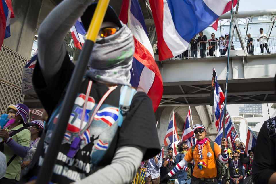 Anti-government protestors wave flags as they march through the Pathumwan district, Sunday, Jan. 12, 2014, in Bangkok, Thailand. Anti-government protesters took over key intersections in Thailand's capital Monday, halting much of the traffic into Bangkok's central business district as part of a months-long campaign to thwart elections and overthrow the democratically elected prime minister. (AP Photo/John Minchillo)