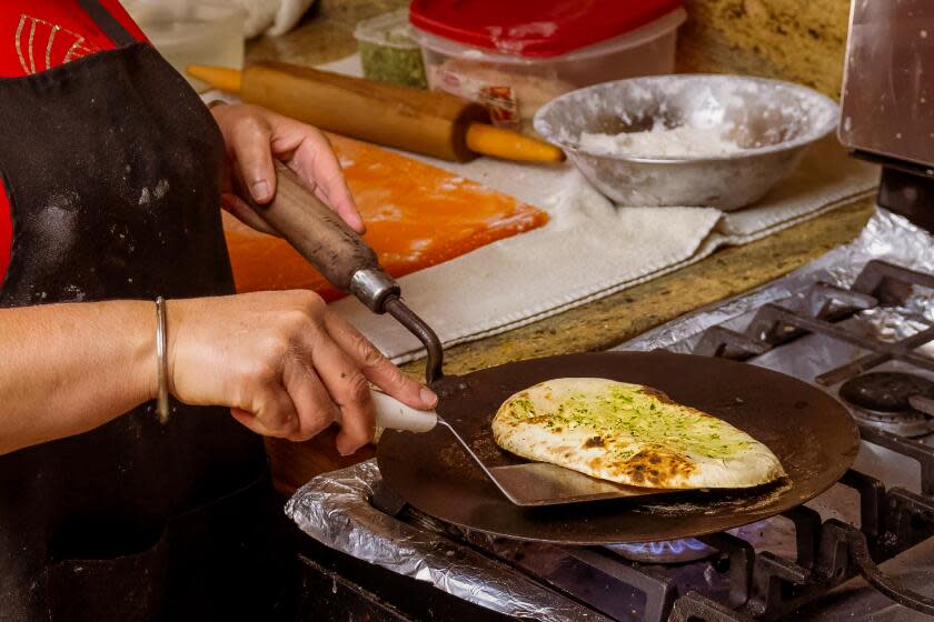 Kulwant "Kimi" Sanghu, chef at Cali Tardka home restaurant, makes and order of naan in Riverside on Friday, July 21, 2023. (Paul Rodriguez / For The Times)