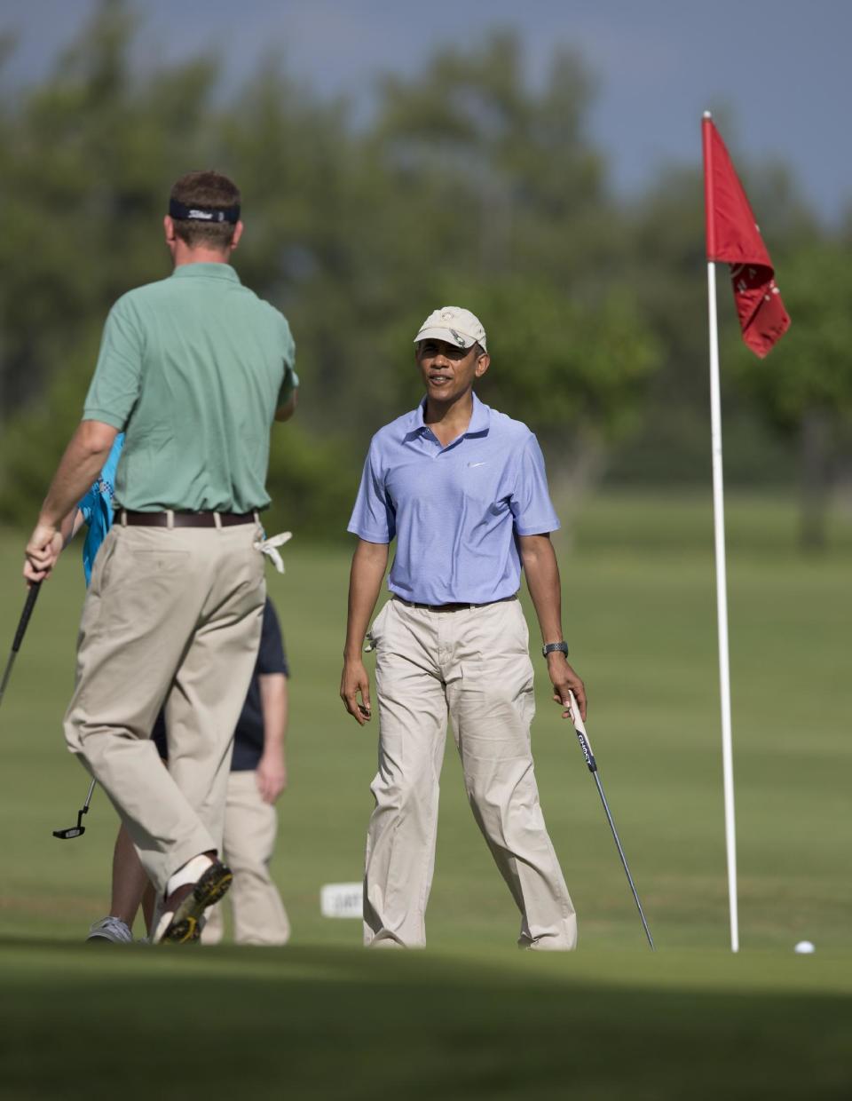 President Barack Obama walks onto the second green to join Marvin Nicholson, left, at Kaneohe Klipper Golf Course on Marine Corps Base Hawaii in Kaneohe Bay, Hawaii, Thursday, Jan. 2, 2014. The first family is in Hawaii for their annual holiday vacation. (AP Photo/Carolyn Kaster)