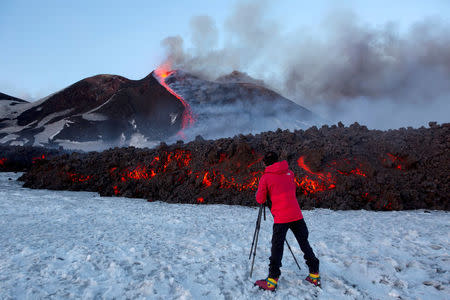 FILE PHOTO A tourist stands in front of Italy's Mount Etna, Europe's tallest and most active volcano, as it spews lava during an eruption on the southern island of Sicily, Italy February 28, 2017. REUTERS/Antonio Parrinello/File photo