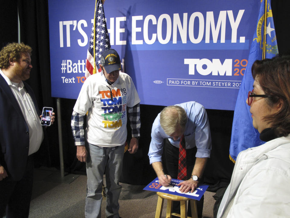 In this Tuesday, Feb. 11, 2020, photo, Democratic presidential hopeful Tom Steyer signs a campaign poster for a U.S. military veteran after speaking to about 200 people during a town hall gathering at the National Automobile Museum in Reno, Nev. The California billionaire says his campaign is "doing fine" despite dismal showings in Iowa and New Hampshire, but has to do "very well" in the Nevada caucuses next up Feb. 22. (AP Photo/Scott Sonner)