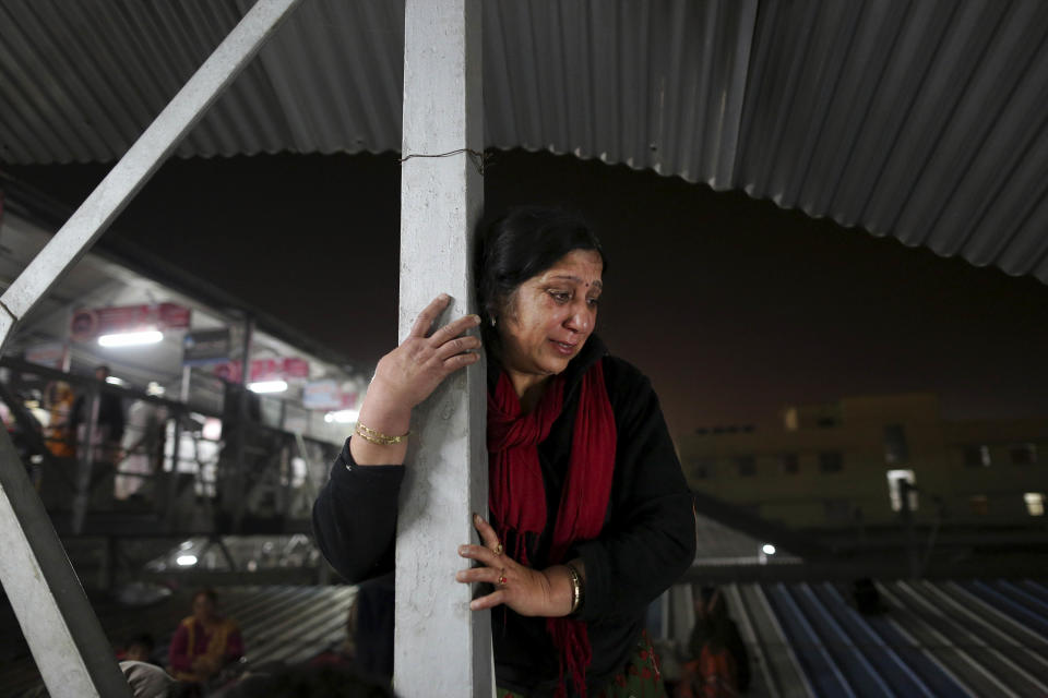 An Indian woman weeps as she watches from a staircase as rescue workers tend to the bodies of those killed in a stampede on a railway platform at the main railway station in Allahabad, India, Sunday, Feb. 10, 2013. At least ten Hindu pilgrims attending the Kumbh Mela were killed and more then thirty were injured in a stampede on an overcrowded staircase, according to Railway Ministry sources. (AP Photo/Kevin Frayer)