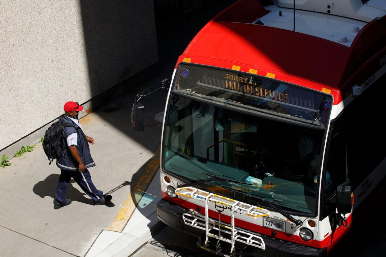 A TTC driver walks past a bus at Scarborough Centre station on Aug. 28, 2023. (Alex Lupul/CBC - image credit)