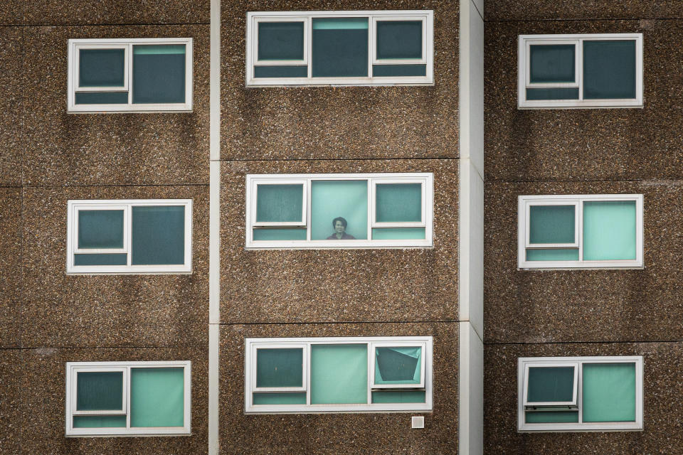 A lone woman looking out the window of her apartment at the North Melbourne Public housing flats.