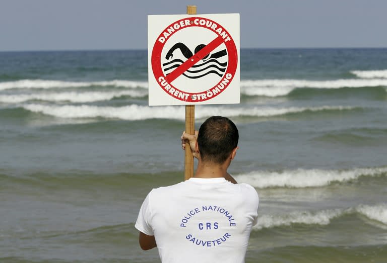 Un CRS maître-nageur-sauveteur installe un panneau indiquant la présence de courants de baïne, le 21 juillet 2004 sur la plage de Lacanau (Patrick BERNARD)