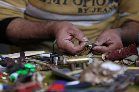 Palestinian diorama artist Majdi Abu Taqeya works on miniature figures he carves from remnants of Israeli ammunition collected from the scenes of border protests along the Israel-Gaza border, in the central Gaza Strip March 11, 2019. Picture taken March 11, 2019. REUTERS/Ibraheem Abu Mustafa
