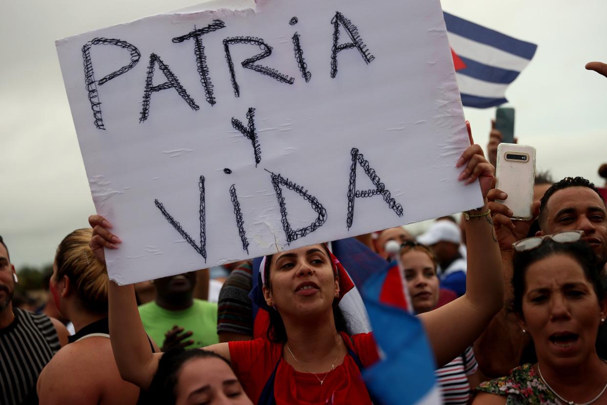 A Cuban protester raises a placard with song ‘Patria y Vida’ written on it (Getty Images)