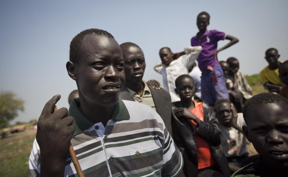 In this photo taken Thursday, Jan. 2, 2014, Phillip Madol, 33, left, one of the thousands who fled the recent fighting between government and rebel forces in Bor by boat across the White Nile, speaks to a reporter in the town of Awerial, South Sudan. Madol was one of Sudan's "Lost Boys," young men who were moved to the United States during the country's old civil war when South Sudan was still part of Sudan, and studied at Grand Rapids Community College in Michigan. (AP Photo/Ben Curtis)