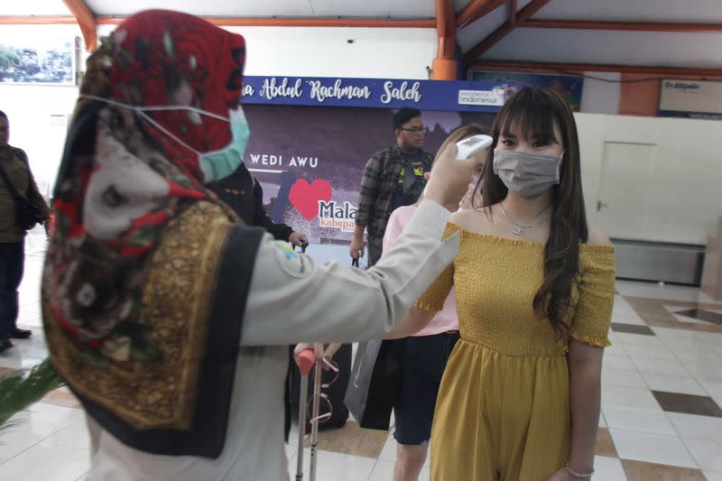 Indonesian health quarantine officer scans the temperature of a passenger with a thermal scanner upon arrival at Abdul Rahman Saleh Airport, East Java, Indonesia