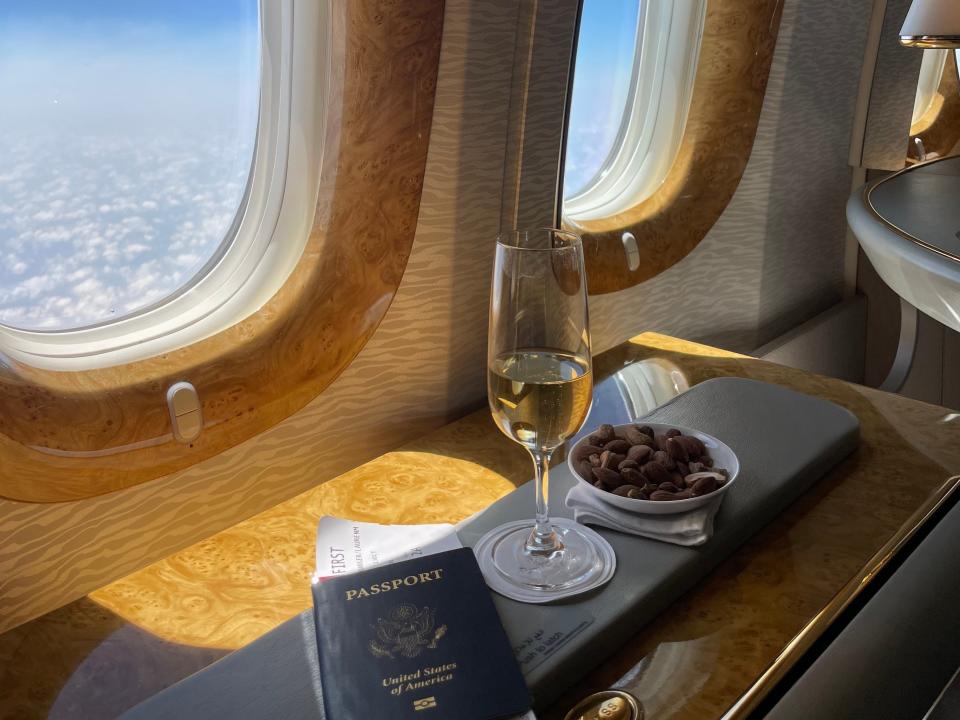 Passport, champagne, food next to window of airplane