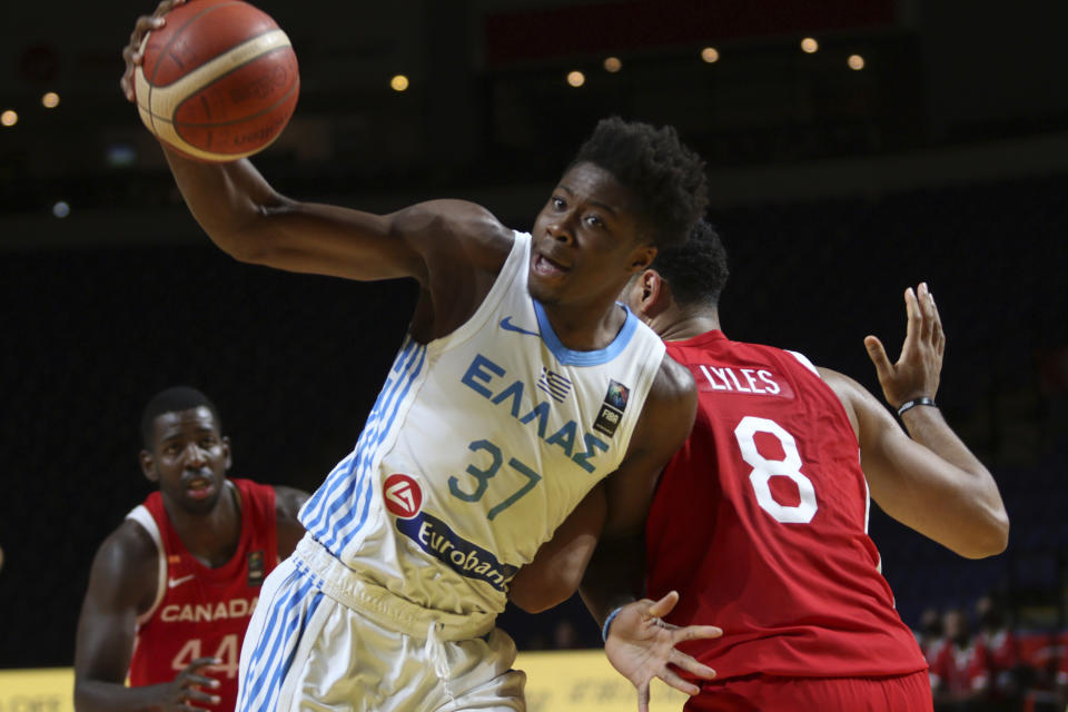 Greece's Kostas Antetokounmpo looks for an open teammate as he moves around Canada's Trey Lyles during the first half of a FIBA men's Olympic qualifying basketball game Tuesday, June 29, 2021 at Memorial Arena in Victoria, British Columbia. (Chad Hipolito/The Canadian Press via AP)