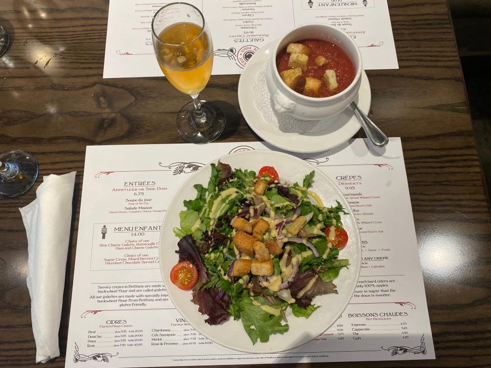 Tomato soup, salad, and cider on table at le creperie de paris at EPCOT