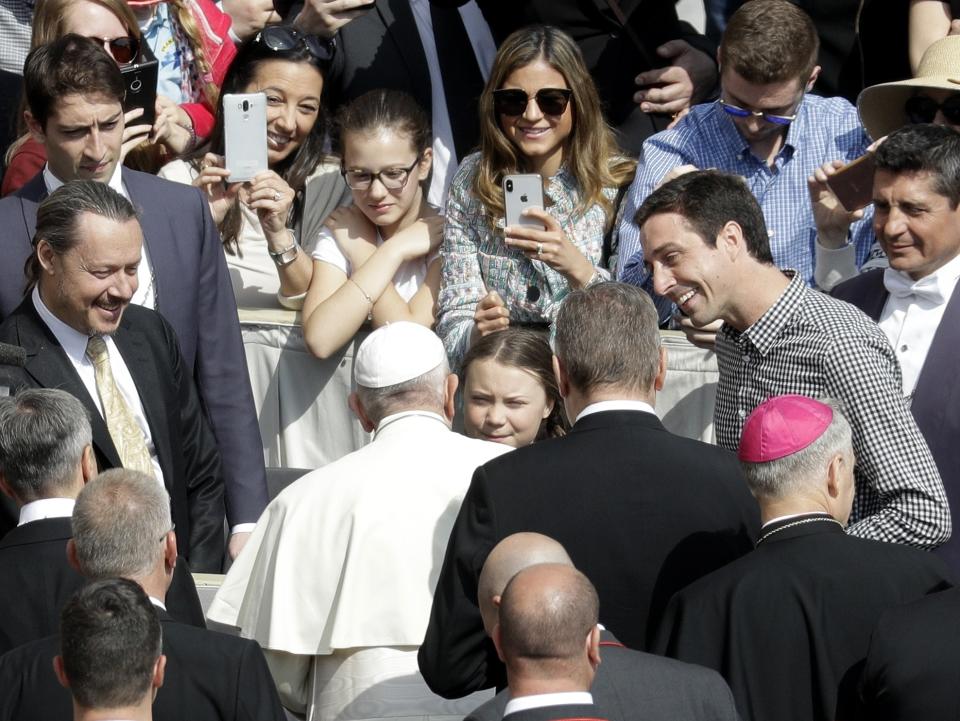 Pope Francis, back to camera, greets Swedish teenage environmental activist Greta Thunberg, center, during his weekly general audience in St. Peter's Square, at the Vatican, Wednesday, April 17, 2019. (AP Photo/Gregorio Borgia)