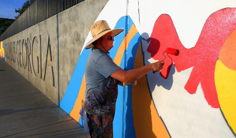 Chris Johnson, a muralist and retired Andrew College professor of art, is leading the design team in painting a mural along the Chattahoochee Riverwalk.The mural stretches along the riverbank’s three-tiered retaining wall where the Synovus Centre, 1111 Bay Ave., overlooks the Riverwalk between two of the most popular attractions on the riverfront: Waveshaper Island and Woodruff Park. 06/15/2023 Mike Haskey/mhaskey@ledger-enquirer.com