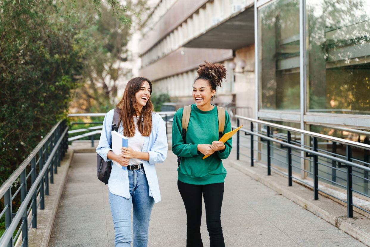 Friends of a university student with textbooks leave the school building