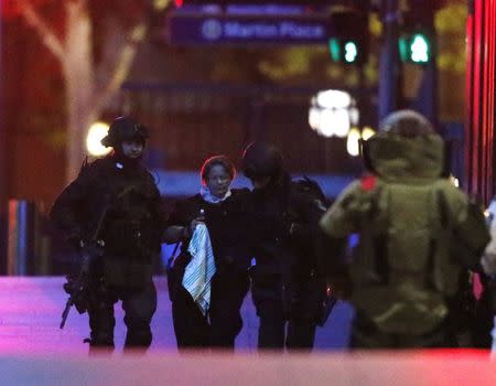 Two heavily armed police officers assist a hostage away from Lindt Cafe in Martin Place in central Sydney December 16, 2014. REUTERS/Jason Reed