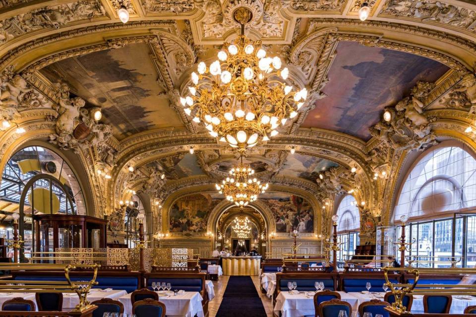 Interior view of elaborate mural ceilings and gold walls of the dining room at Le Train Bleu