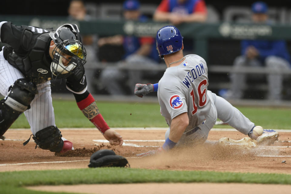 Chicago Cubs' Patrick Wisdom (16) slides safely into home plate on a Frank Schwindel single while Chicago White Sox catcher Yasmani Grandal, left, misses the throw during the first inning of a baseball game at Guaranteed Rate Field, Saturday, May 28, 2022, in Chicago. (AP Photo/Paul Beaty)