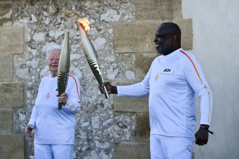 L'ancien footballeur français Basile Boli (d) allume le flambeau de Colette Cataldo, supportrice historique de l’OM, dans le cadre des relais de la flamme olympique et paralympique à la basilique Notre Dame de la Garde, à Marseille, le 9 mai 202 (CHRISTOPHE SIMON)